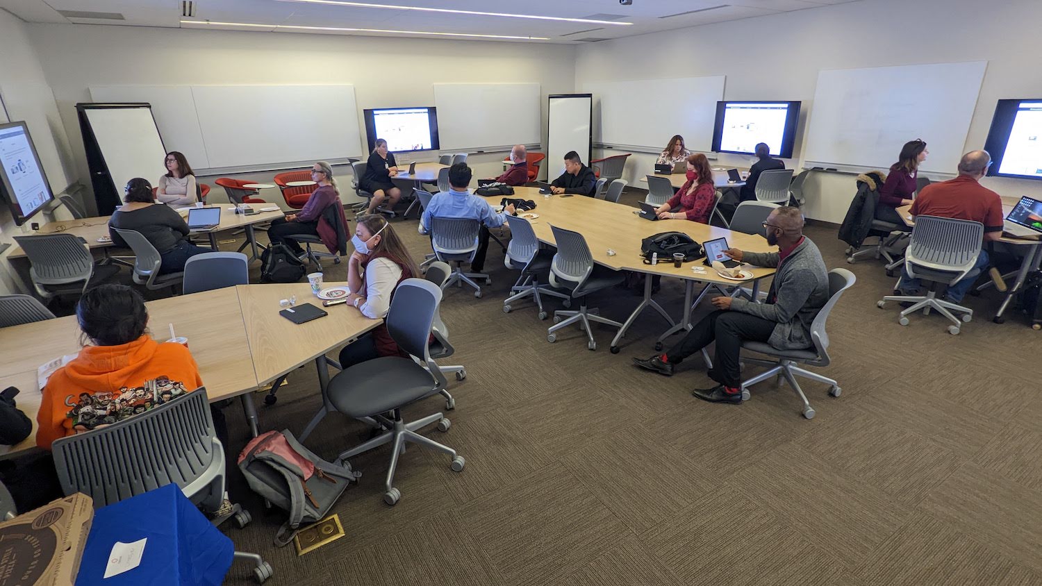 A large group of faculty meeting in a large meeting room around tables