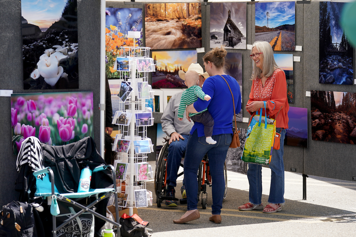 Woman with baby checks out a vendor's art booth